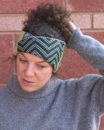 Close image of a model wearing a knitted headband with a c cross over feature.