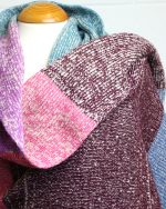 Close image of a knitted blanket scarf, the scarf has a ribbed knitted structure.