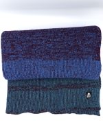 Image of a scarf, rolled up and knitted with purple, green, burgundy and blue hues.