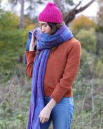 Close image of a model wearing a purple blanket scarf and pink beanie from Wonky Woolies.